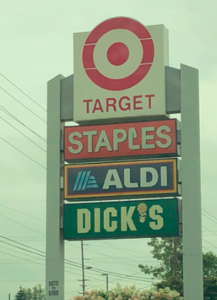 Retail signs arranged so that stores are shown in this order: Target, Staples, Aldi Dicks